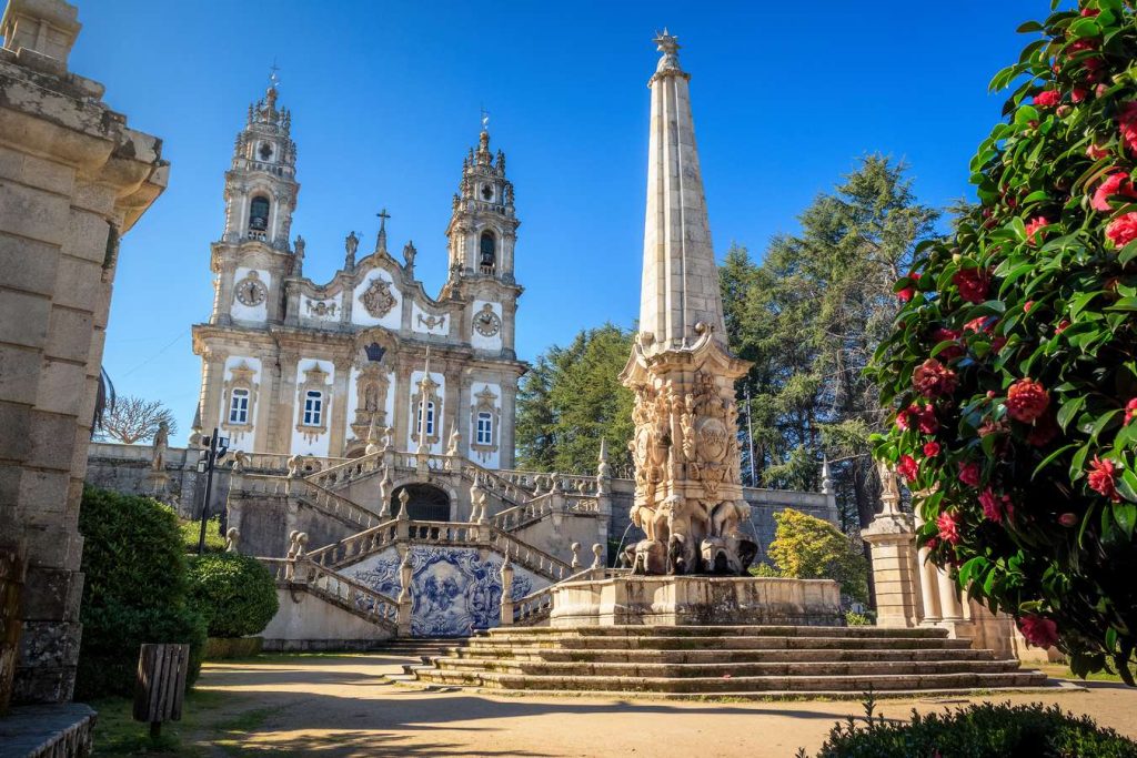 Scenic view of the Sanctuary of Our Lady of Remedies in Lamego, Portugal, featuring ornate architecture and vibrant flowers.