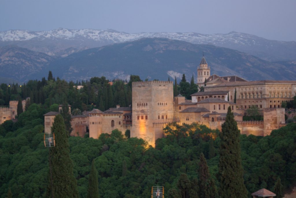 The Alhambra palace complex in Granada, Spain, sits before the Sierra Nevada mountains at dusk.