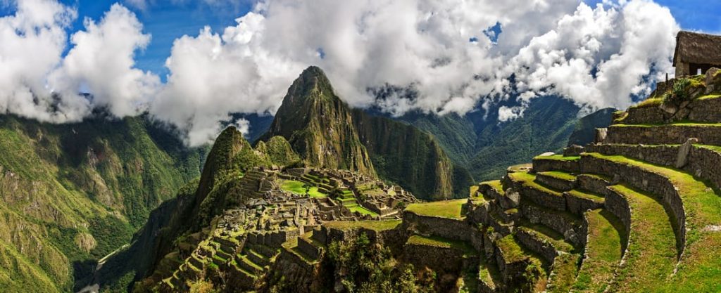Panoramic view of Machu Picchu, the ancient Inca citadel in Peru, nestled in the Andes Mountains with terraced landscapes and stone structures.