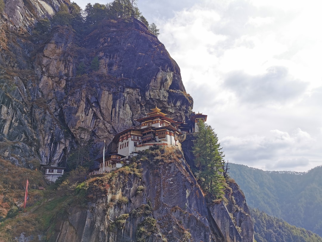 Cliffside Tiger's Nest Monastery in Bhutan, golden roofs, white walls, nestled on a steep, rocky cliff face.