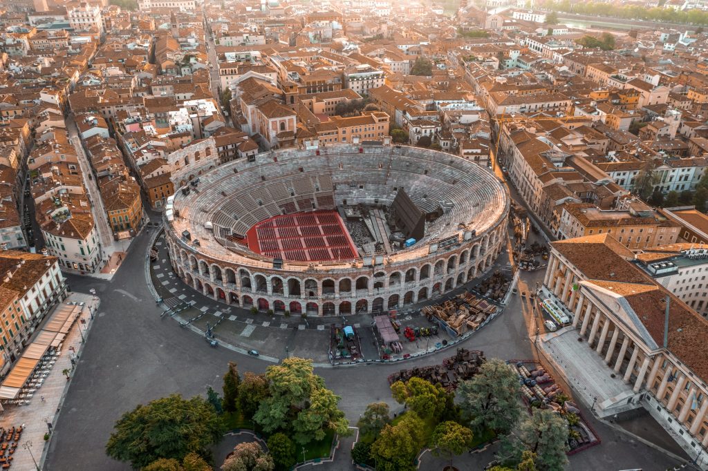 Aerial view of Verona Arena, an ancient Roman amphitheater in Italy, surrounded by city buildings and trees.