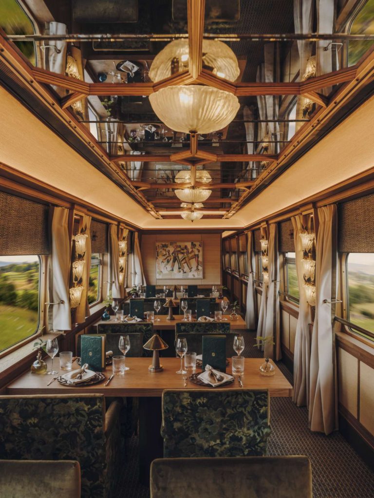 Interior of a luxury train dining car with set tables, elegant decor, and scenic views.