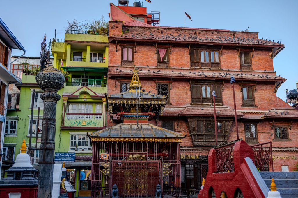 Colorful buildings and temples in Kathmandu, Nepal, featuring red brick and green painted structures.