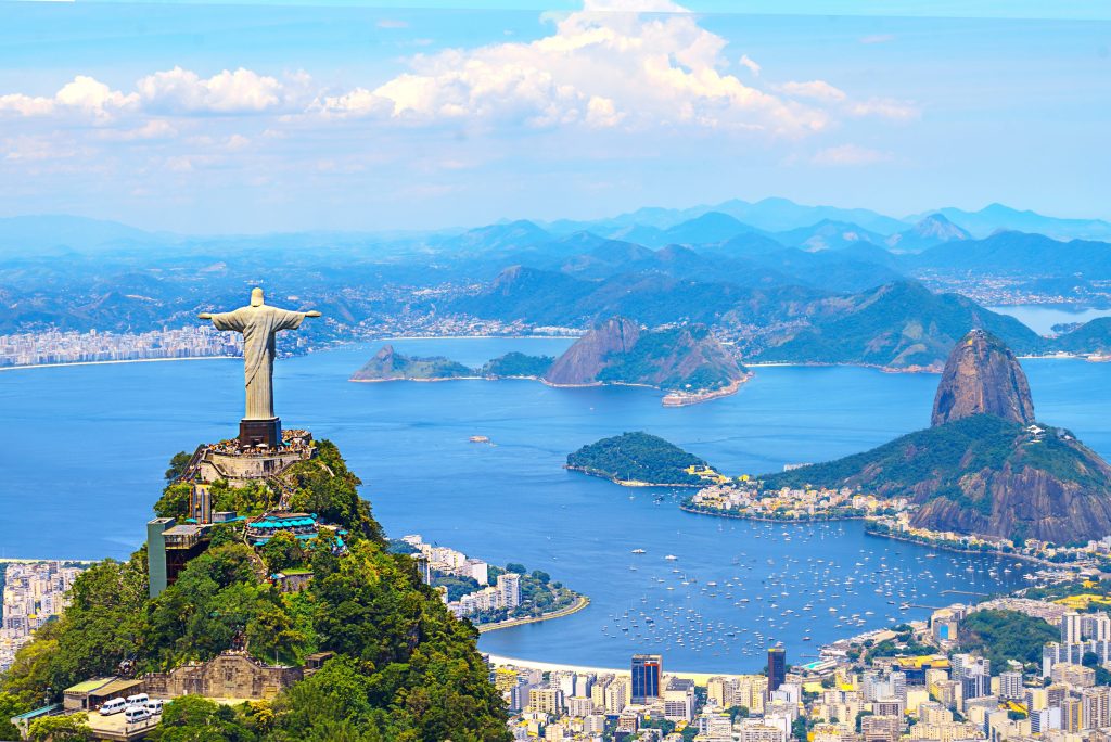 Scenic view of Christ the Redeemer statue atop Corcovado Mountain, overlooking Rio de Janeiro bay and cityscape.