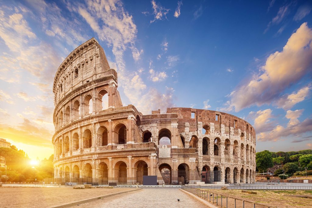 The Colosseum in Rome, Italy, stands majestically under a blue sky with scattered clouds at sunset.