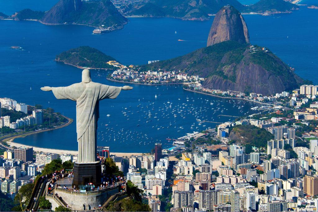 Christ the Redeemer statue overlooks Rio de Janeiro, Brazil, with Sugarloaf Mountain and Guanabara Bay in the background.