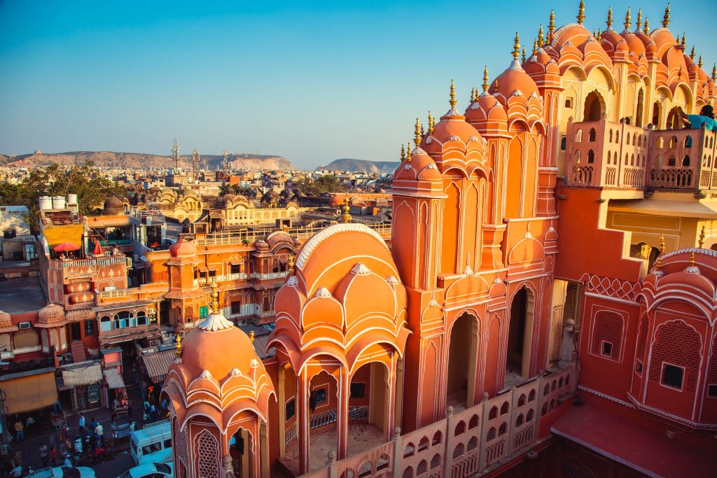 Hawa Mahal, Jaipur, India, features pink sandstone architecture, domes, and arches under a clear blue sky.