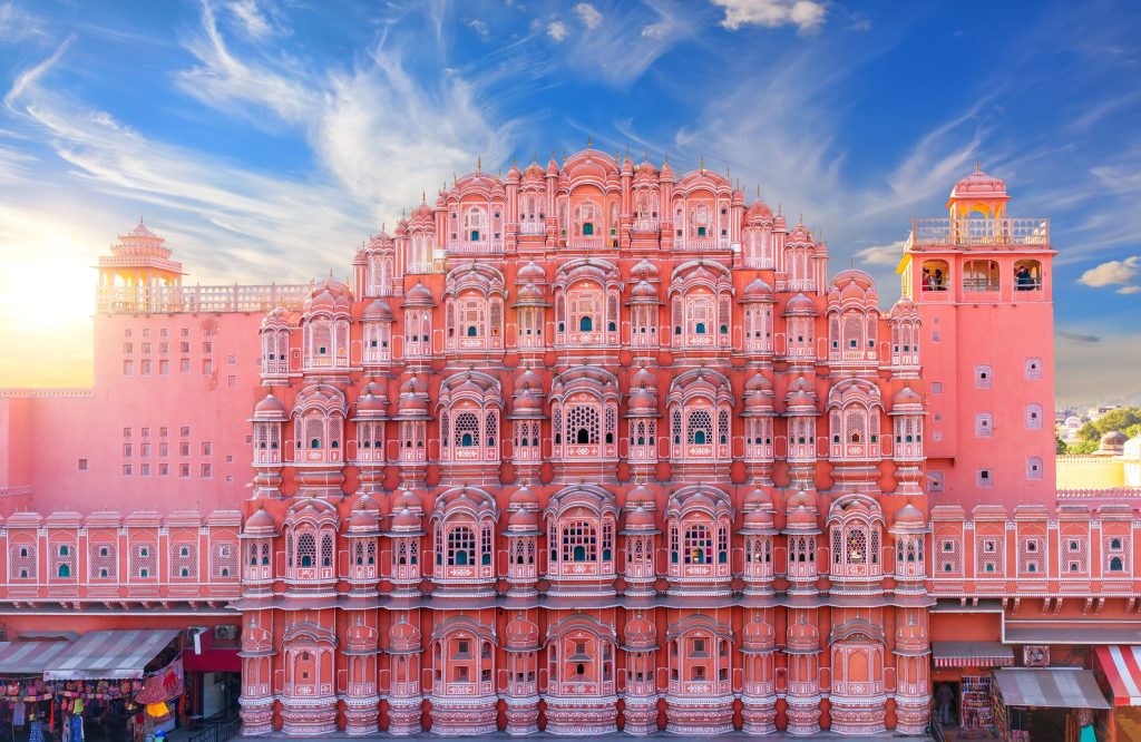 The Hawa Mahal, a pink palace in Jaipur, India, features ornate windows under a blue sky.