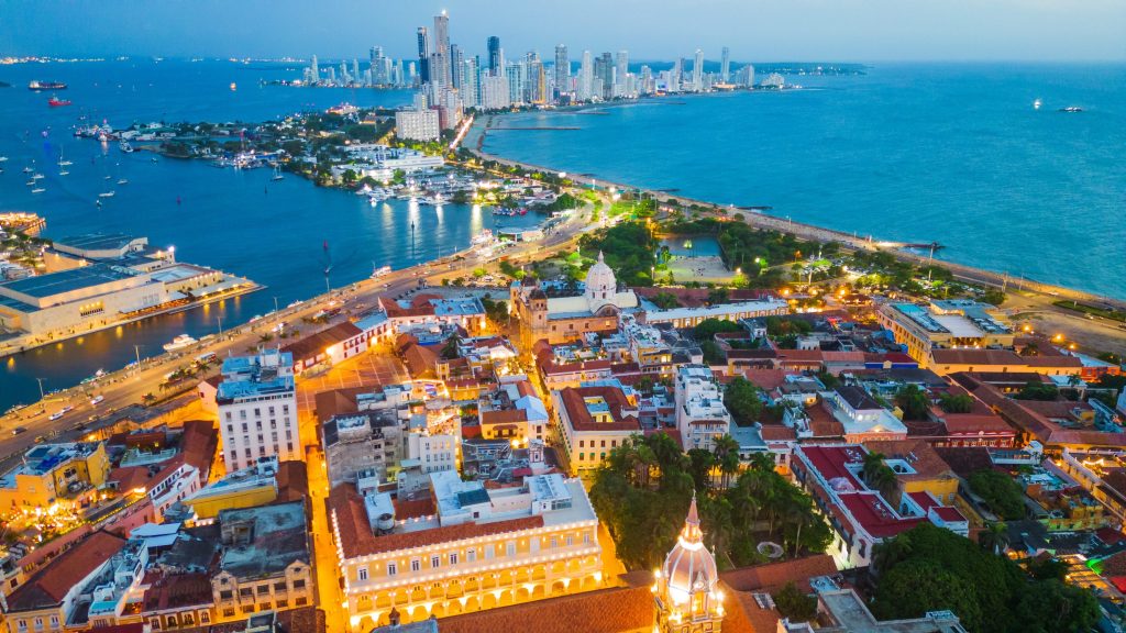 Aerial view of Cartagena, Colombia at dusk, featuring colorful buildings and ocean coastline.
