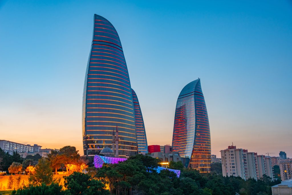 Three flame-shaped skyscrapers, the Flame Towers, stand tall in Baku, Azerbaijan, illuminated at dusk.