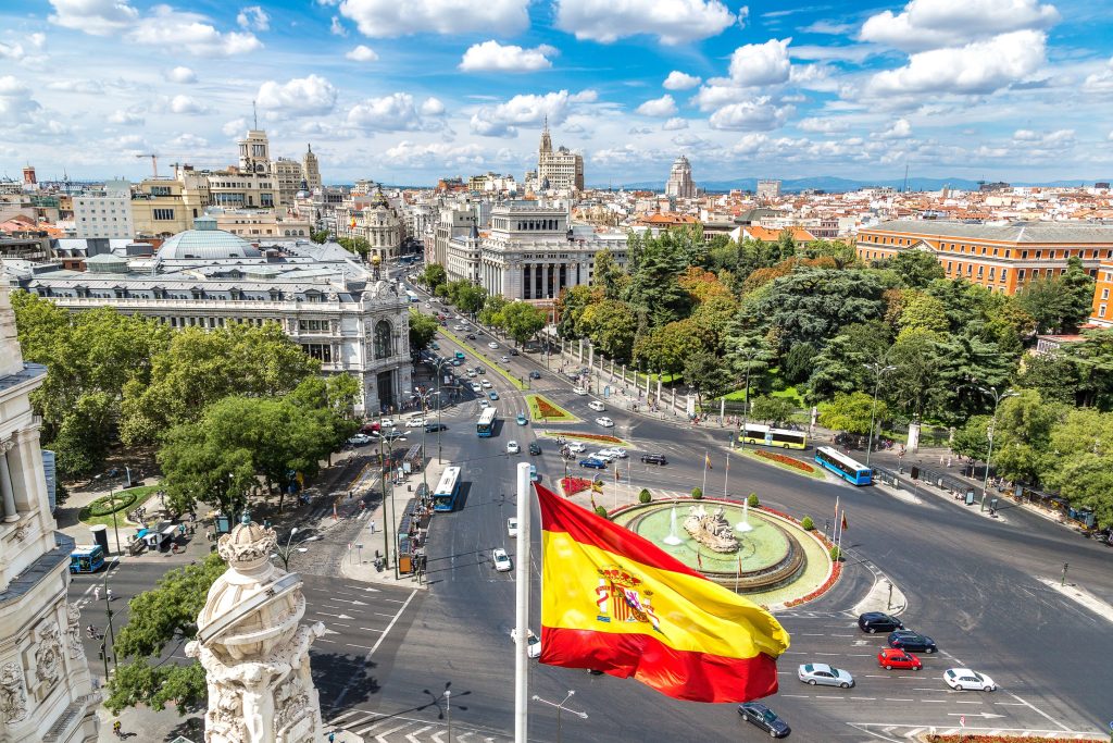 Aerial view of Madrid, Spain with Spanish flag waving over a roundabout with fountain.